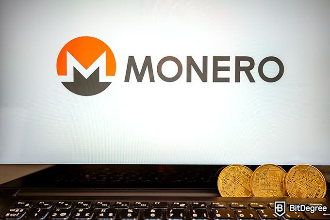 Moneroマイニング：コンピューター画面の前に積み上げられたMoneroコイン。